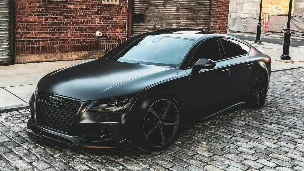 Matte black Audi A7 parked on a brick street with premium window tint applied.