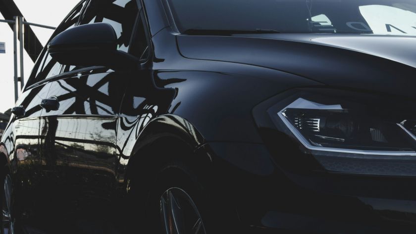 A close-up side profile of a dark car parked outdoors, showcasing the appearance of window glass treated with ceramic tint.